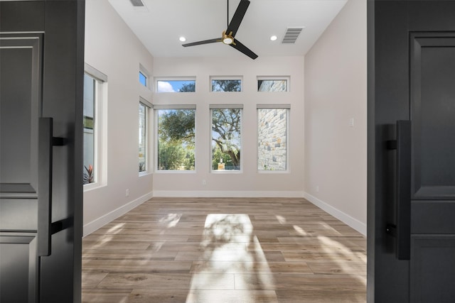 unfurnished dining area with ceiling fan and light wood-type flooring