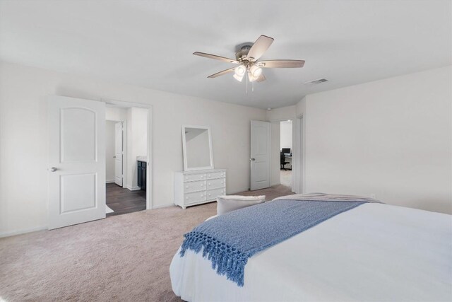 carpeted bedroom with connected bathroom and ceiling fan