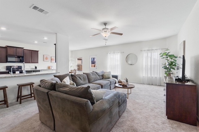 carpeted living room with ceiling fan