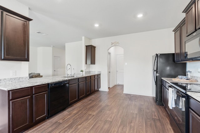 kitchen featuring dark brown cabinetry, sink, dark hardwood / wood-style floors, kitchen peninsula, and black appliances