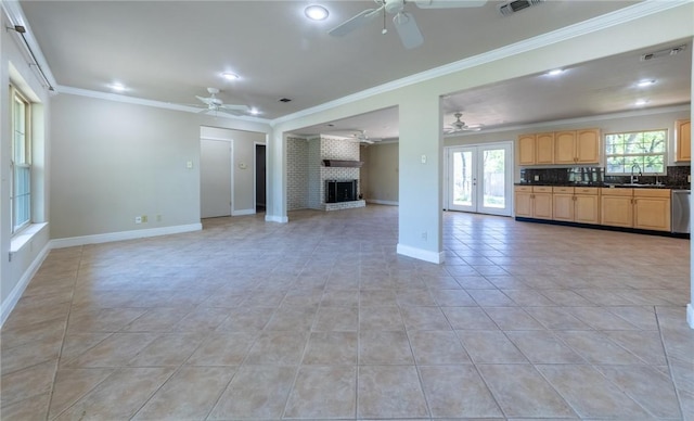 unfurnished living room with sink, crown molding, light tile patterned floors, a fireplace, and french doors