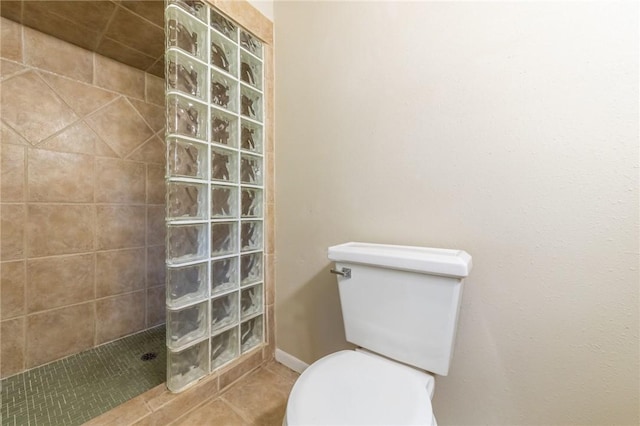 bathroom featuring tile patterned floors, toilet, and a tile shower