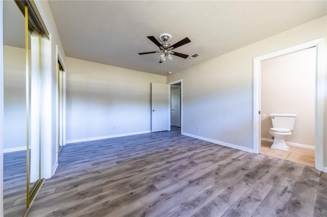 unfurnished bedroom featuring ceiling fan, wood-type flooring, and connected bathroom