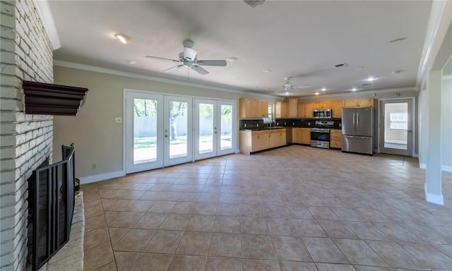 kitchen with crown molding, light tile patterned floors, appliances with stainless steel finishes, ceiling fan, and a fireplace