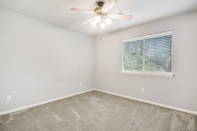 carpeted spare room featuring ceiling fan and baseboards