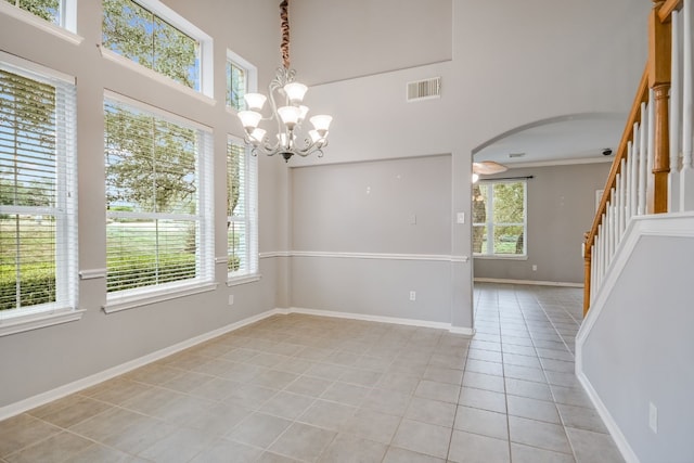 spare room featuring light tile patterned floors, visible vents, arched walkways, stairs, and a wealth of natural light