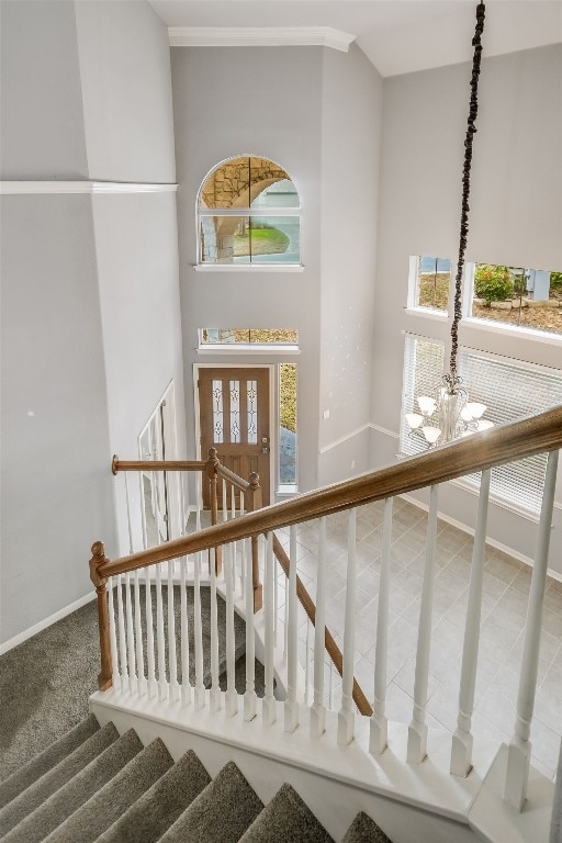 staircase featuring a chandelier, a high ceiling, and baseboards