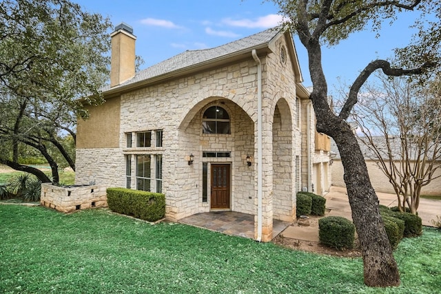 exterior space with a yard, a patio, a chimney, and stone siding