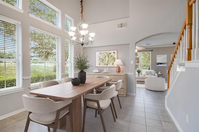 dining area featuring arched walkways, light tile patterned floors, visible vents, stairway, and plenty of natural light