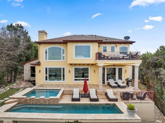 back of house with ceiling fan, an outdoor living space, a patio area, a balcony, and an in ground hot tub