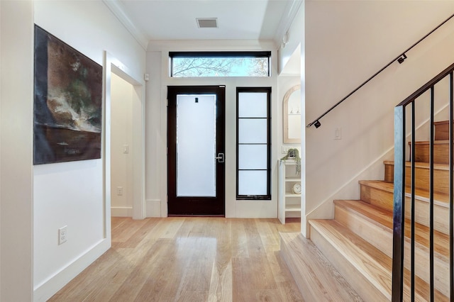 foyer featuring ornamental molding and light wood-type flooring