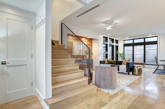 staircase with wood-type flooring, expansive windows, and ceiling fan