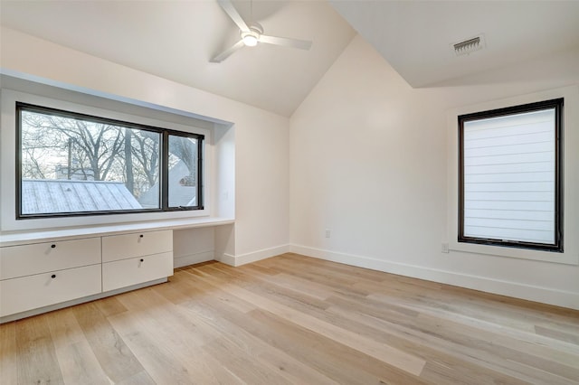 unfurnished bedroom featuring ceiling fan, built in desk, vaulted ceiling, and light wood-type flooring