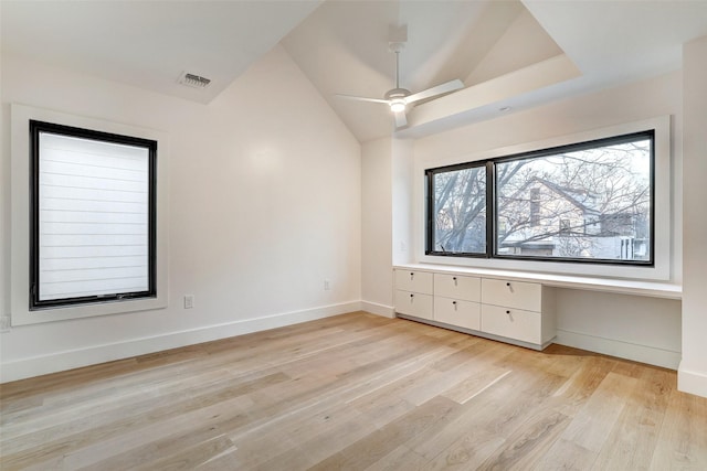 spare room with ceiling fan, lofted ceiling, built in desk, and light wood-type flooring