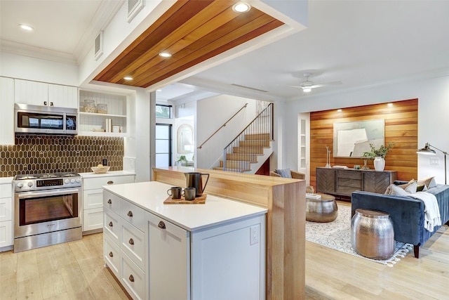 kitchen featuring a center island, light hardwood / wood-style flooring, appliances with stainless steel finishes, white cabinets, and backsplash