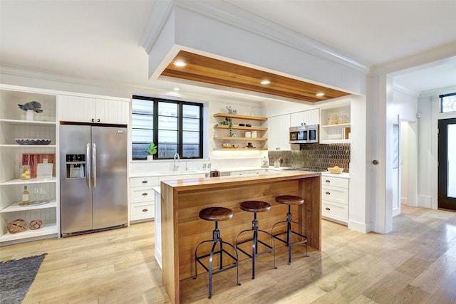 kitchen featuring appliances with stainless steel finishes, white cabinetry, sink, a kitchen breakfast bar, and a center island