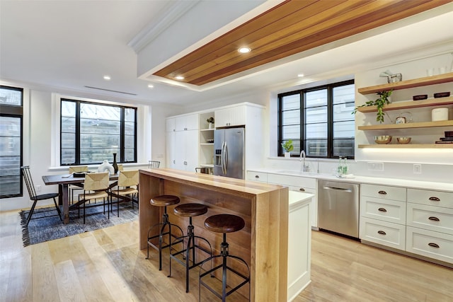 kitchen with sink, a breakfast bar area, white cabinets, light hardwood / wood-style floors, and stainless steel appliances