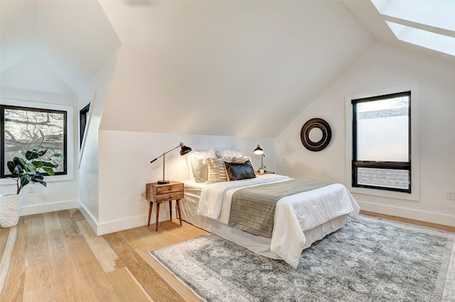 bedroom featuring hardwood / wood-style floors and vaulted ceiling with skylight