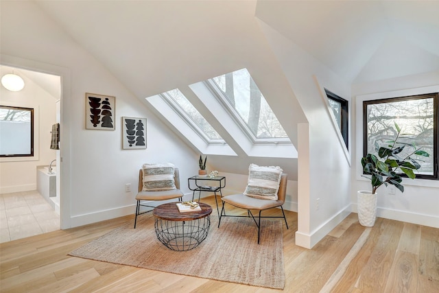 living area with a skylight and light hardwood / wood-style flooring