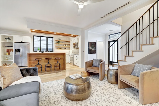 living room featuring crown molding, sink, ceiling fan, and light wood-type flooring