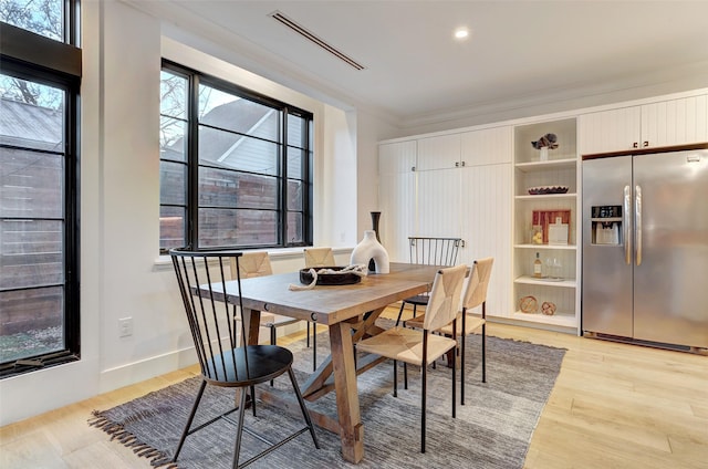 dining space featuring ornamental molding and light hardwood / wood-style flooring