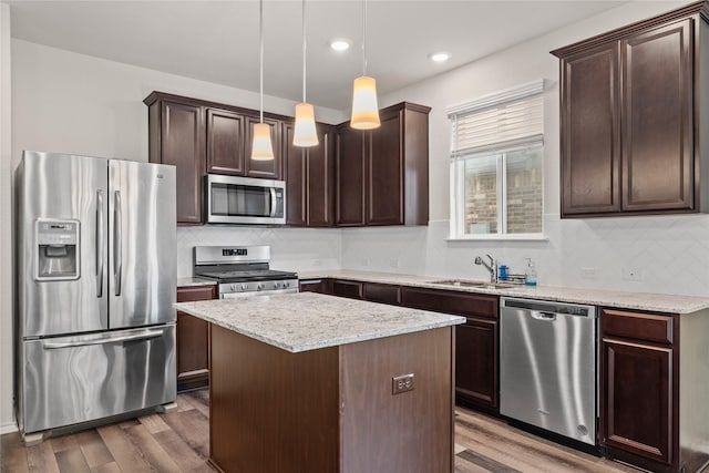 kitchen featuring sink, dark wood-type flooring, hanging light fixtures, stainless steel appliances, and a center island