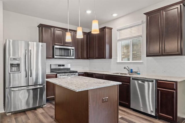 118 Grace Lilly Dr, Buda, TX 78610 - kitchen featuring appliances with stainless steel finishes, dark brown cabinetry, wood finished floors, tasteful backsplash, and a center island