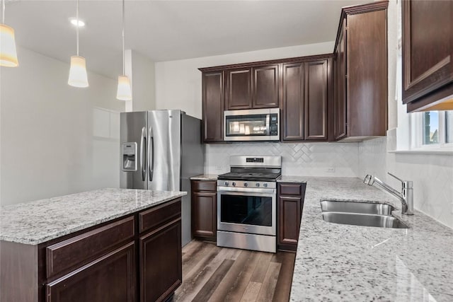 118 Grace Lilly Dr, Buda, TX 78610 - kitchen with stainless steel appliances, dark wood finished floors, decorative backsplash, dark brown cabinets, and light stone counters