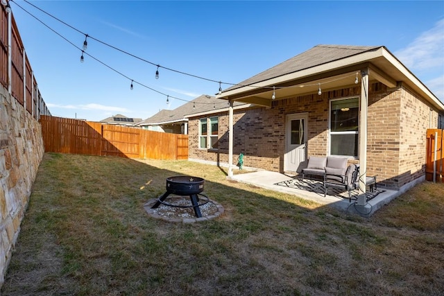 118 Grace Lilly Dr, Buda, TX 78610 - rear view of house featuring brick siding, an outdoor fire pit, a fenced backyard, and a patio