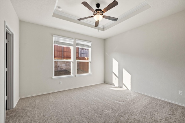 carpeted empty room featuring a raised ceiling, ornamental molding, and ceiling fan