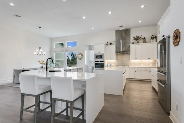 kitchen with stainless steel appliances, hanging light fixtures, a large island, and wall chimney exhaust hood