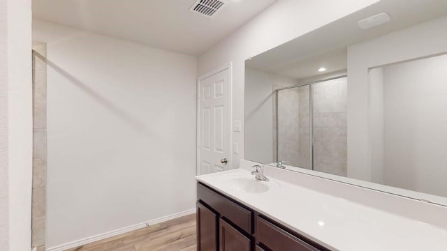 bathroom featuring wood-type flooring, a shower with shower door, and vanity