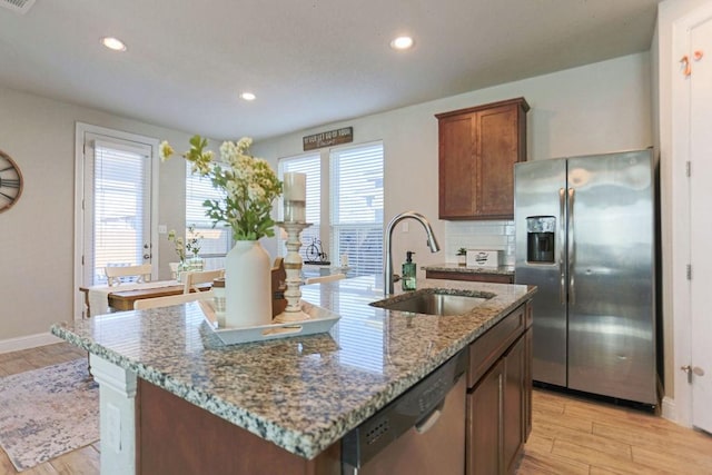 kitchen featuring an island with sink, appliances with stainless steel finishes, sink, and light hardwood / wood-style flooring