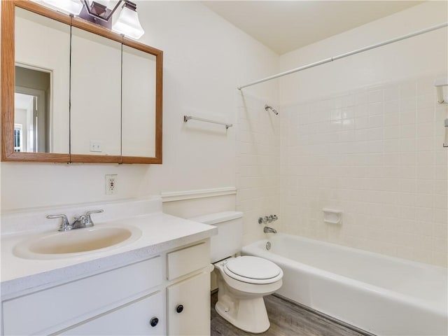 full bathroom featuring tiled shower / bath combo, vanity, hardwood / wood-style floors, and toilet