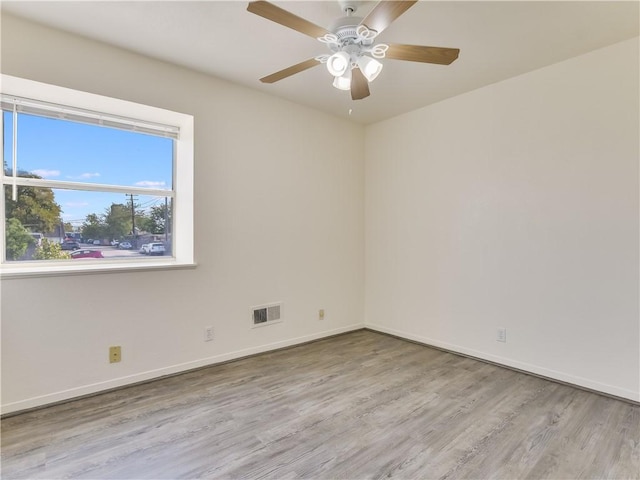 empty room with ceiling fan and light hardwood / wood-style flooring