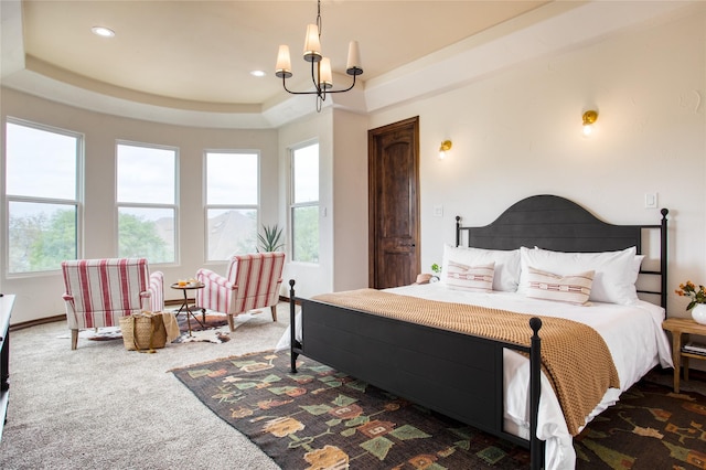 bedroom featuring an inviting chandelier, a raised ceiling, and dark colored carpet