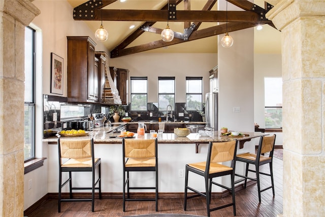 kitchen with stainless steel fridge, kitchen peninsula, plenty of natural light, and a kitchen bar