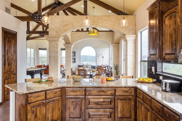 kitchen featuring high vaulted ceiling, plenty of natural light, pendant lighting, and beam ceiling