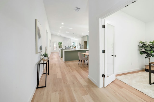 hallway with lofted ceiling and light hardwood / wood-style flooring