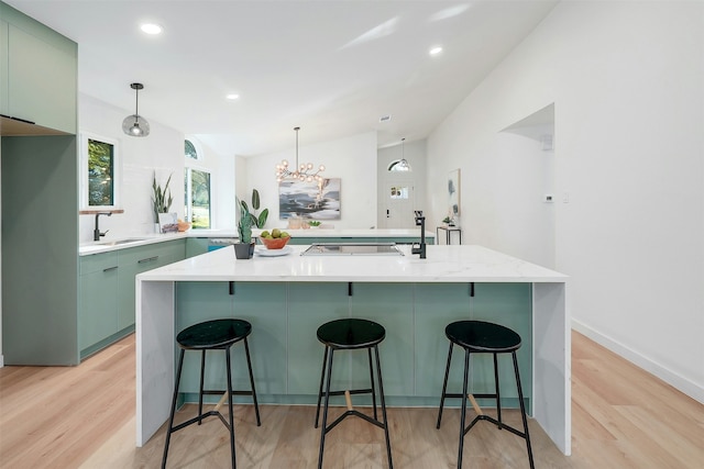 kitchen with an island with sink, sink, a breakfast bar area, and light hardwood / wood-style floors