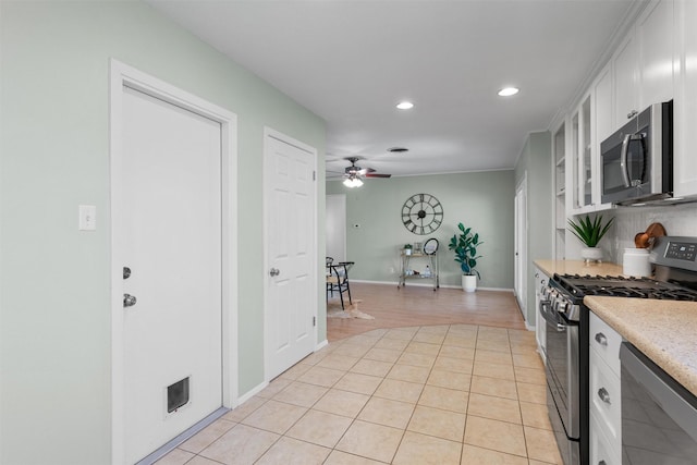 kitchen with light tile patterned floors, ceiling fan, appliances with stainless steel finishes, tasteful backsplash, and white cabinets