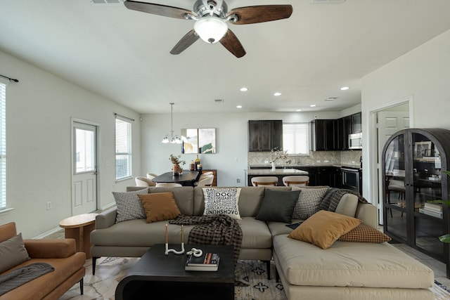 living room with plenty of natural light and ceiling fan with notable chandelier