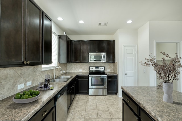 kitchen featuring sink, backsplash, stainless steel appliances, dark brown cabinetry, and light tile patterned flooring