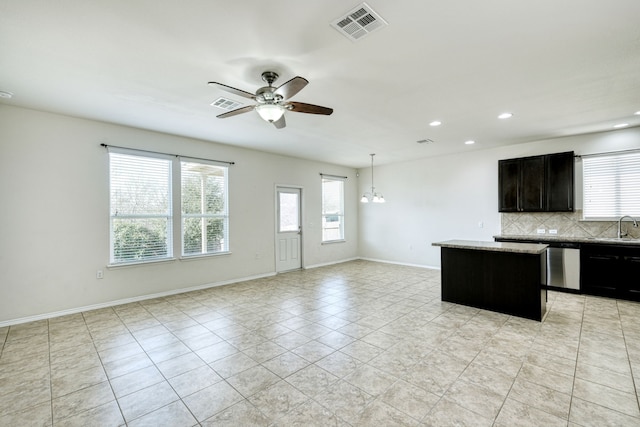 kitchen featuring ceiling fan with notable chandelier, sink, backsplash, hanging light fixtures, and a center island