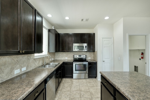 kitchen featuring sink, tasteful backsplash, dark brown cabinets, light tile patterned floors, and stainless steel appliances