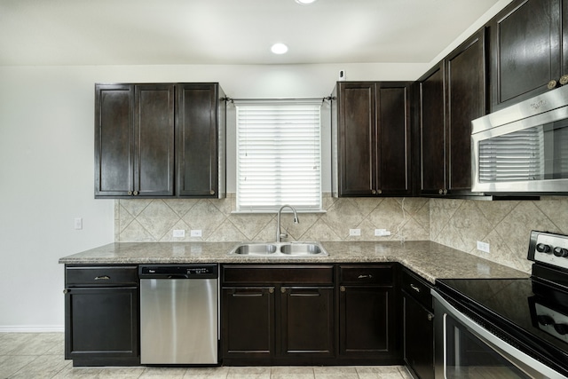 kitchen with sink, appliances with stainless steel finishes, dark brown cabinetry, light stone countertops, and decorative backsplash