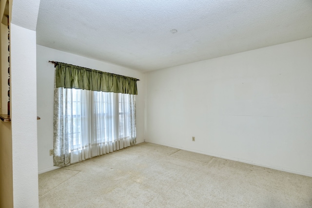 empty room with light carpet and a textured ceiling