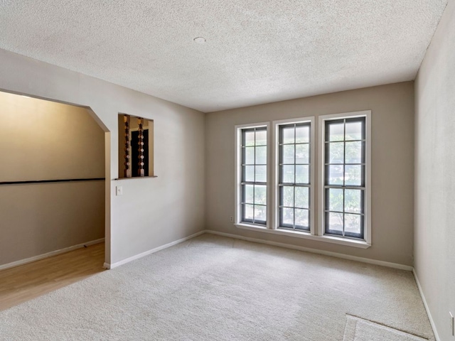 spare room with carpet floors, a textured ceiling, and baseboards