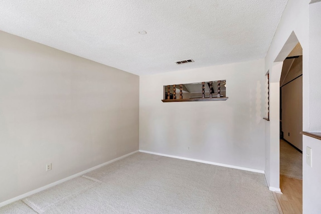 carpeted empty room featuring a textured ceiling and baseboards