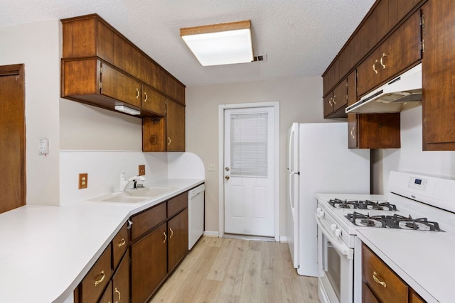 108 Fairlane Dr, Round Rock, TX 78664 - kitchen with white appliances, under cabinet range hood, light countertops, light wood-type flooring, and a textured ceiling